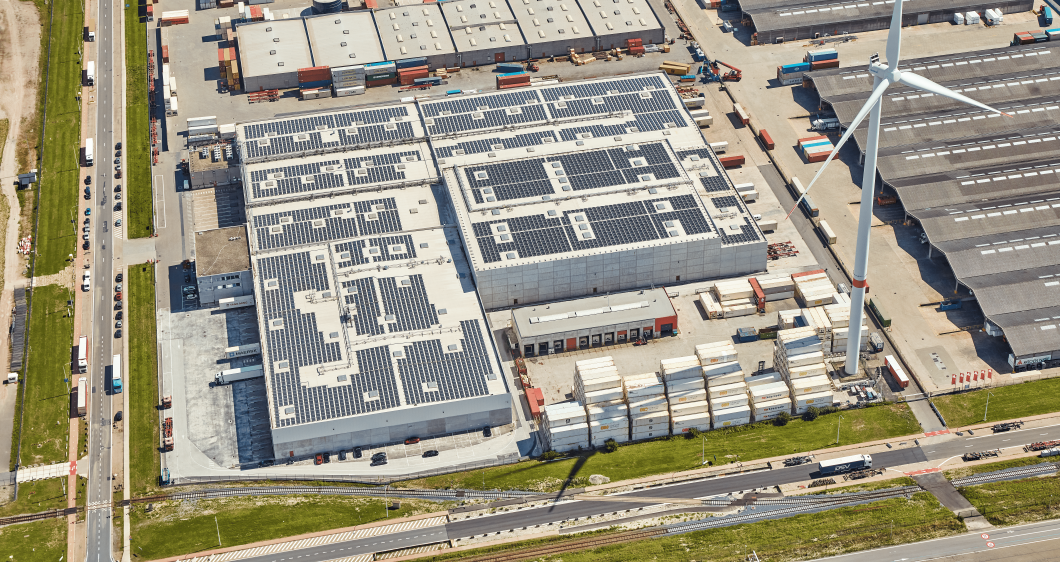 Widok z lotu ptaka na chłodnię z panelami słonecznymi i turbiną wiatrową w Belgii