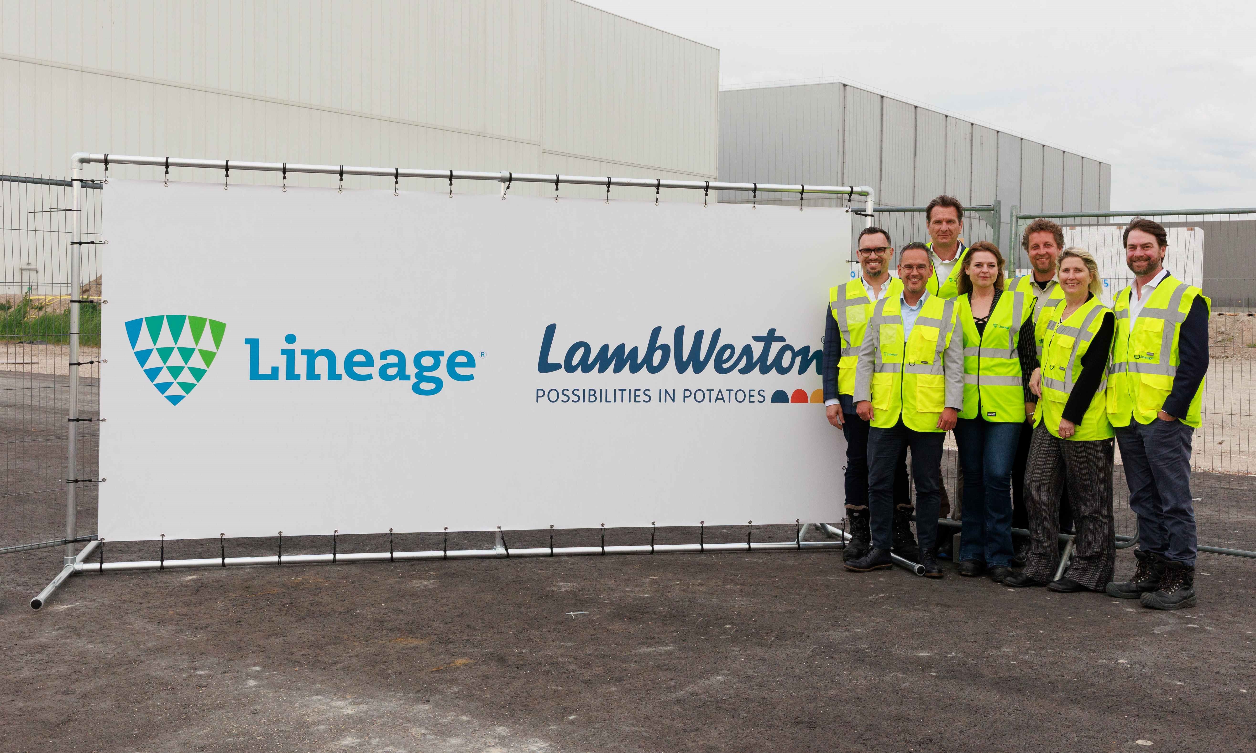 A group of people in high visibility gear stand near a sign announcing Lineage's expansion with customer Lamb Weston