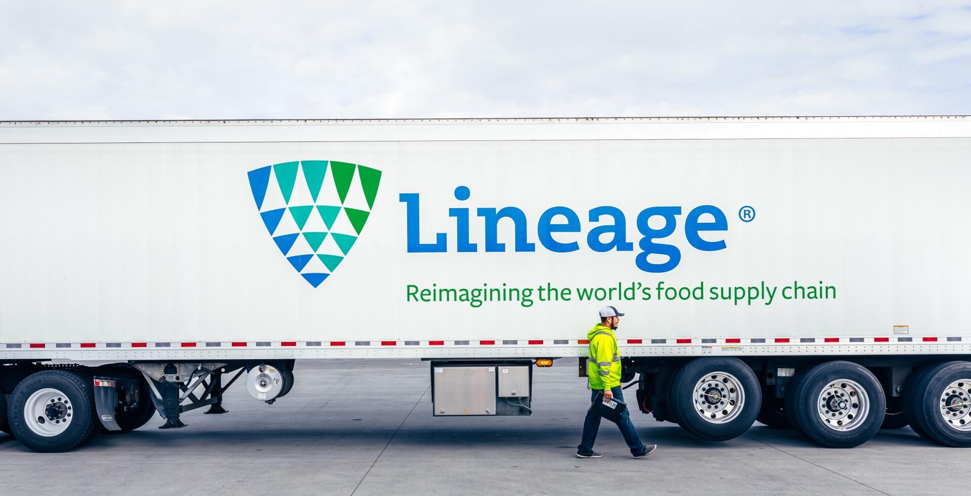 Un miembro del equipo de Lineage camina delante de un camión de transporte con control de temperatura de Lineage, lo que simboliza las soluciones integradas a nivel mundial de Lineage.
