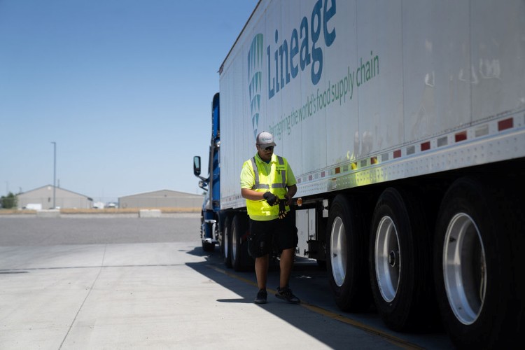 Lineage team member inspecting a refrigerated trailer beside a parked truck in a distribution yard, supporting transportation operations for temperature-sensitive products.