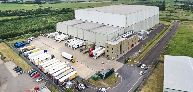 Aerial view of Lineage’s Wisbech – Boleness automated cold storage warehouse in the UK, with multiple trucks at the loading docks.