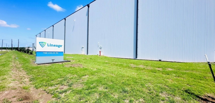 Exterior of Lineage’s Cold Port facility in Houston, Texas, showing the large white warehouse wall and the Lineage sign along the grassy front lawn on a clear day.