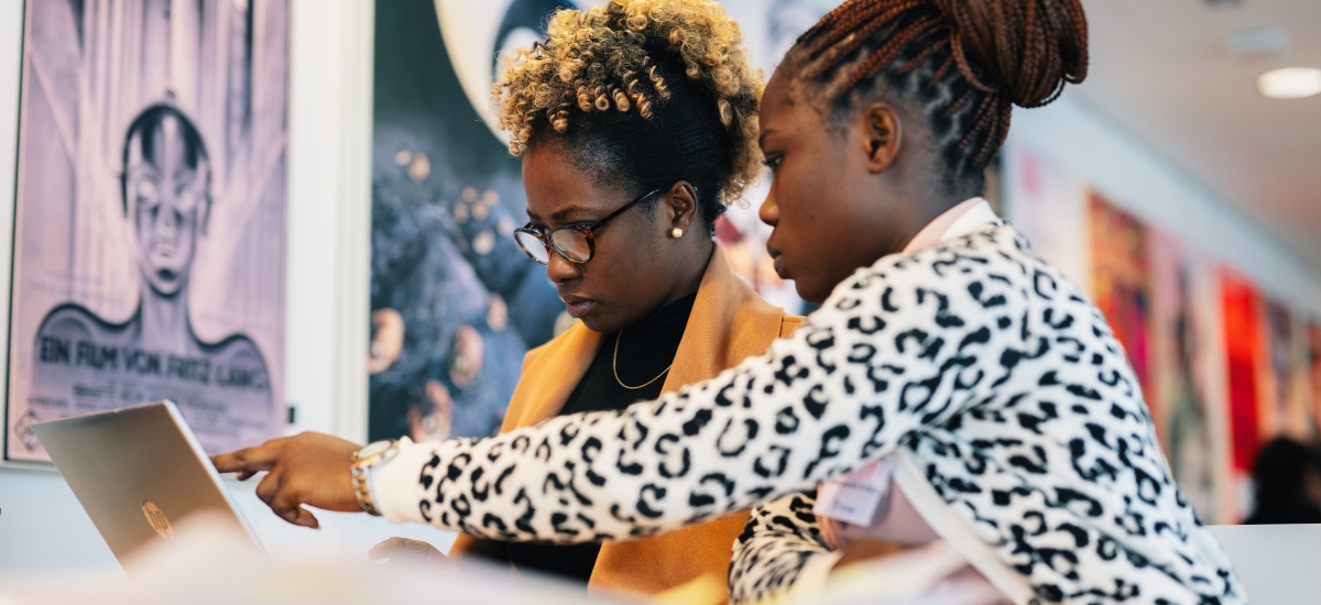 Two women work on a laptop