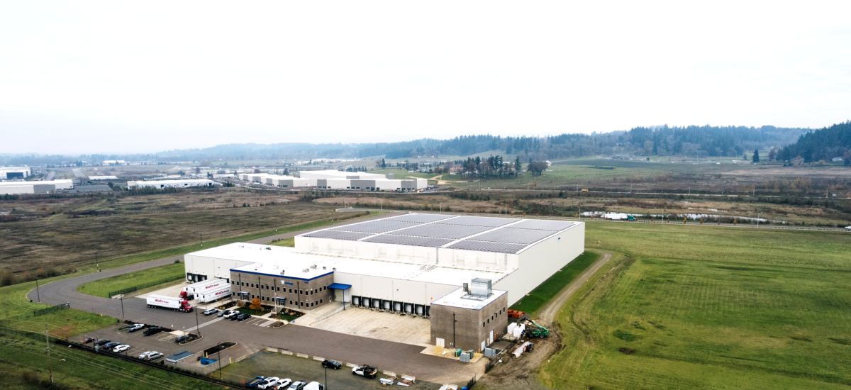 An aerial view of Lineage's cold storage warehouse in Salem, OR shows the building has solar panels on the roof