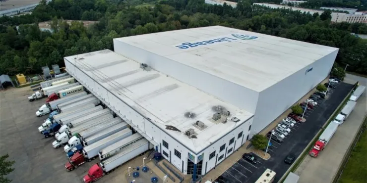 Exterior view of Lineage's College Park cold storage warehouse in Atlanta, GA, with multiple loading docks, parked trucks, and surrounding green landscape, supporting efficient cold chain logistics.