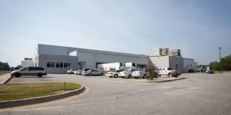 Exterior view of Lineage’s Macon cold storage facility in Atlanta, Georgia, featuring a white warehouse with loading docks, fenced perimeter and a small office area.