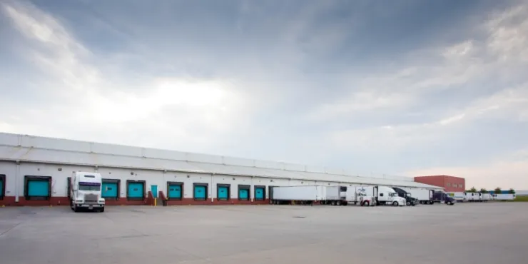 Dockside view of Lineage’s McDonough -  200 King Mill cold storage facility, featuring multiple loading bays, semi-trailers, and a spacious concrete yard.