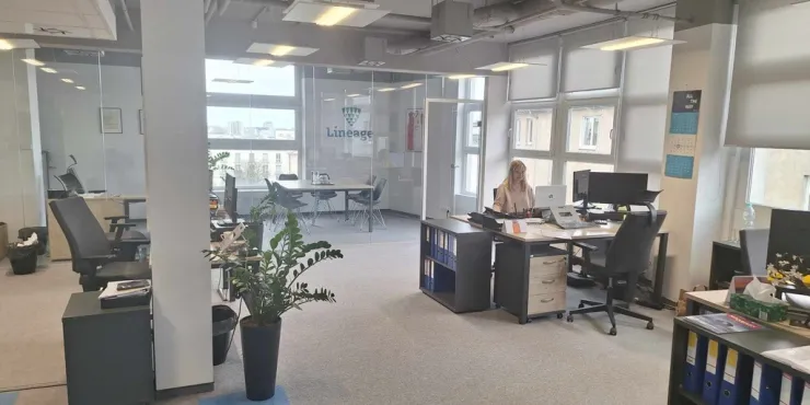 Modern Lineage office space in Gdynia, Poland, featuring an open workspace with desks, computers, and a glass-walled conference room, supporting freight forwarding and logistics operations.