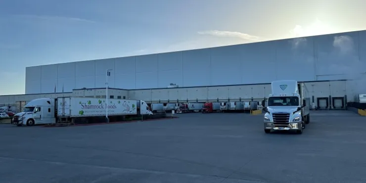 Il magazzino frigorifero Lineage a Pasco, nello Stato di Washington, con diverse banchine di carico, camion in sosta e un ampio piazzale pavimentato all'alba, garantisce l'efficienza delle operazioni della catena del freddo.