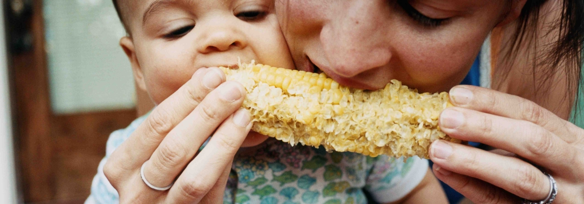 A mother and child share corn on the cob