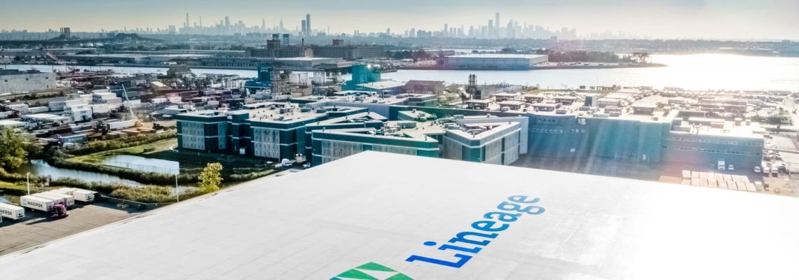 Vista aérea de una instalación de almacenamiento en frío de Lineage cerca de un puerto importante, con el horizonte de la ciudad al fondo.