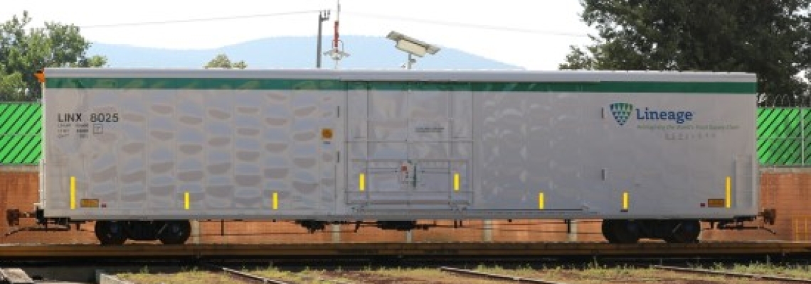 Side view of a silver Lineage LINX insulated railcar sitting on railroad tracks, featuring the Lineage logo and reflective safety markings, with trees and mountains visible in the background.