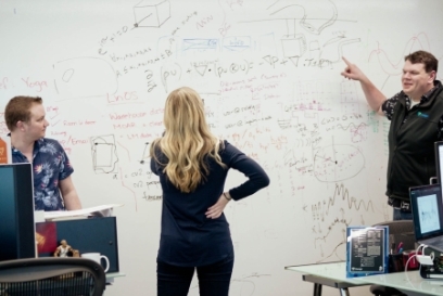 Lineage team members collaborating in an office, reviewing and discussing supply chain concepts and data sketched across a whiteboard during a working session.
