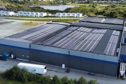 Vista aerea del centro di stoccaggio Lineage a Haugesund, in Norvegia, con pannelli solari sul tetto, aree di carico e il paesaggio residenziale e naturale circostante.