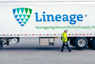 Lineage refrigerated trailer parked at a warehouse with an employee walking beside it, highlighting temperature-controlled transportation and logistics operations.