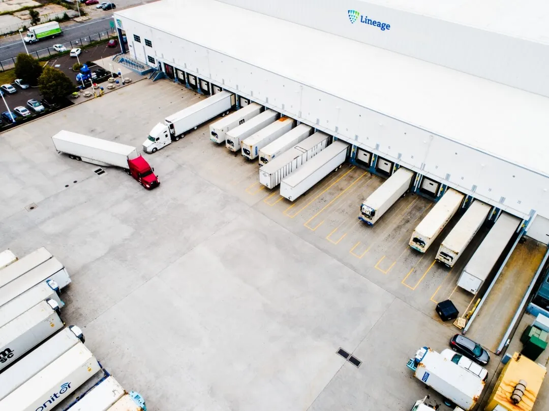 Aerial view of Lineage facility with refrigerated trucks loading and unloading at multiple docks, representing foodservice distribution and last-mile delivery operations.