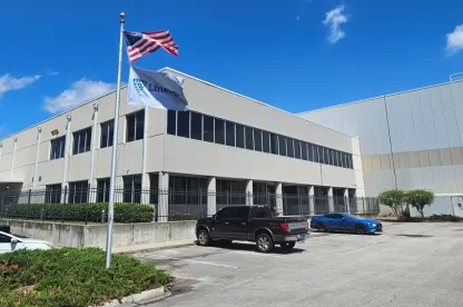 Exterior view of Lineage’s Dignan cold storage facility in Jacksonville, Florida, showcasing the modern building design and prominently displayed flags under a clear blue sky.