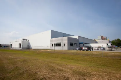 Exterior view of Lineage’s Macon cold storage facility in Atlanta, Georgia, featuring a white warehouse with loading docks, fenced perimeter, and a small office area.