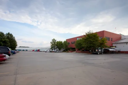 Exterior view of Lineage’s McDonough - 200 King Mill cold storage facility, featuring a red-brick office building, spacious parking lot, and multiple docked trucks.
