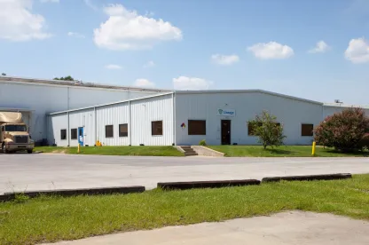 Exterior view of Lineage’s Unadilla cold storage facility near Atlanta, Georgia, featuring a white warehouse with a small office entrance, parked truck, and surrounding greenery.