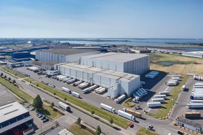Aerial view of Lineage’s Bergen op Zoom, Netherlands cold storage facility in the Netherlands, featuring multiple loading bays and refrigerated trucks for drayage and distribution.