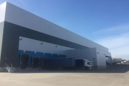 Modern ambient cold storage warehouse with multiple loading docks and trailers at Lineage’s Belle Eau Park facility in Bilsthorpe, UK.