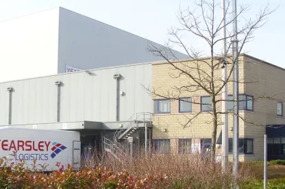 Vista frontale del magazzino frigorifero automatizzato Hams Hall Lineagea Coleshill, nel Regno Unito, con un camion della Yearsley Logistics e un cartello che indica il punto di raccolta antincendio.