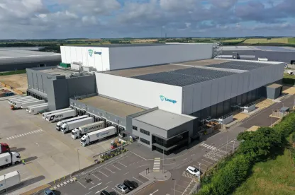 Vista dall'alto del magazzino frigorifero Lineagea Peterborough, dotato di pannelli solari sul tetto e circondato da moderni edifici industriali e strade.