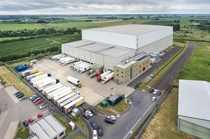Aerial view of Lineage’s Wisbech – Boleness automated cold storage warehouse in the UK, with multiple trucks at the loading docks.