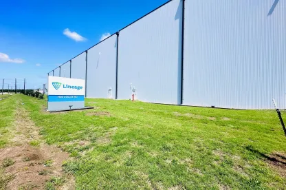 Exterior of Lineage’s Cold Port facility in Houston, Texas, showing the large white warehouse wall and the Lineage sign along the grassy front lawn on a clear day.