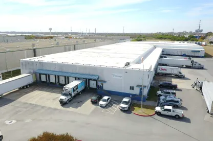 Aerial view of Lineage’s San Antonio Frost Bank Center facility, showing the white warehouse, loading docks, trailers and parked vehicles on a clear day.